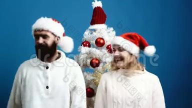 戴着<strong>新年帽</strong>子`男人和女人在圣诞树上玩得很开心。 庆祝<strong>新年</strong>和圣诞节的概念。